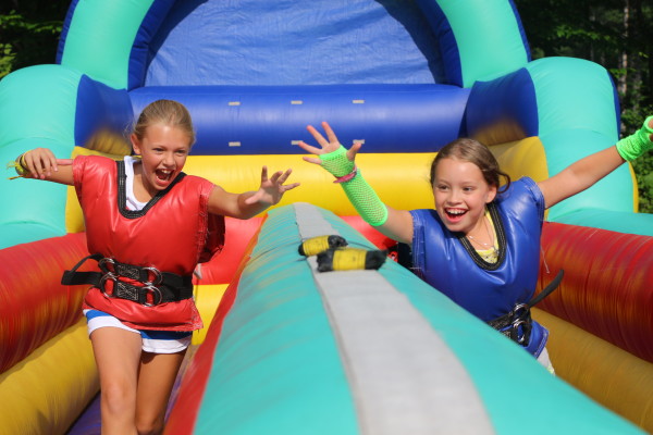 two girls playing in inflatable obstacle course at camp Kippewa