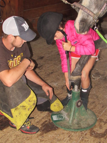 Horseback riders learn from farrier about caring for horses at all girls equestrian horseback riding camp in Maine
